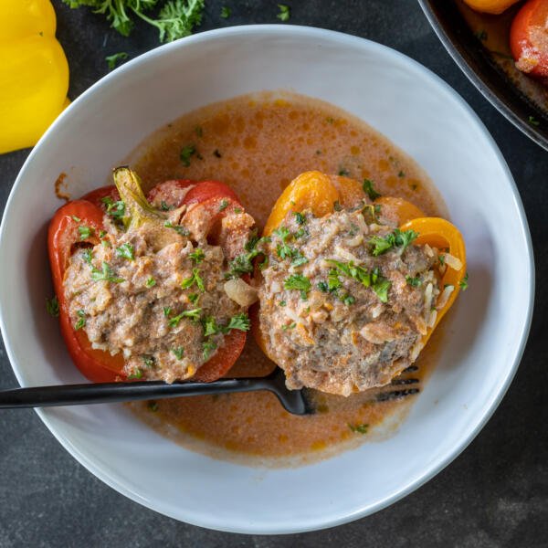 Stuffed peppers in a bowl with sauce.