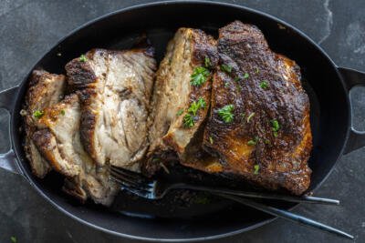 Pork roast on a pan with utensils.