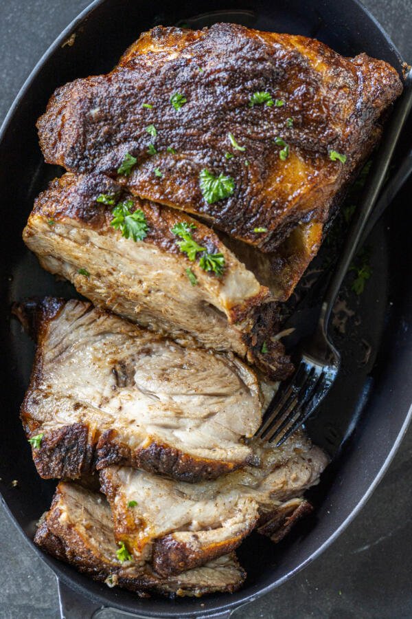 Sliced Roasted pork on a pan with herbs. 