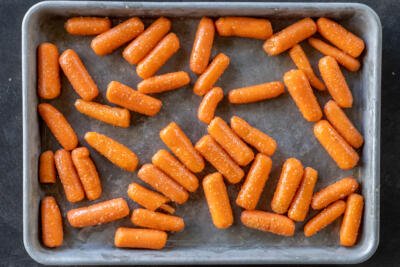Seasoned baby carrots on a baking sheet.