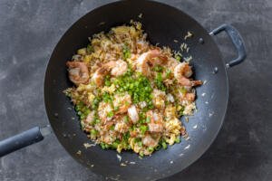 Cooked fried rice in a pan with green onions.