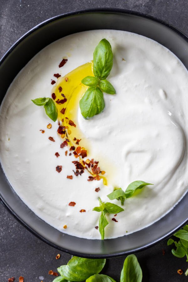 Whipped Feta Dip in a bowl with herbs and oil. 