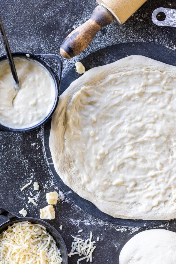 Stretched out pizza dough with sauce and cheese.