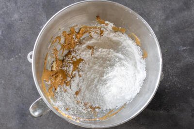 Powdered sugar added to butter in a mixing bowl.