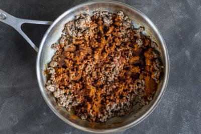 Ground beef with seasoning in a pan.