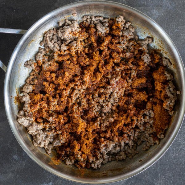 Ground beef with seasoning in a pan.