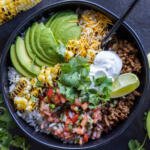 Burrito Bowl with veggies and herbs next to it.