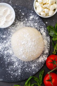 Pizza dough on a floured surface with toppings