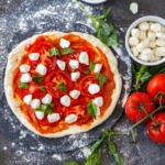 Pizza dough with red sauce and tomatoes