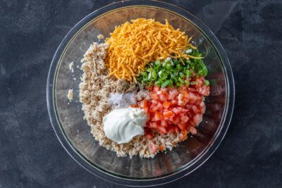 Tuna, cheese, veggies and mayo in a bowl.