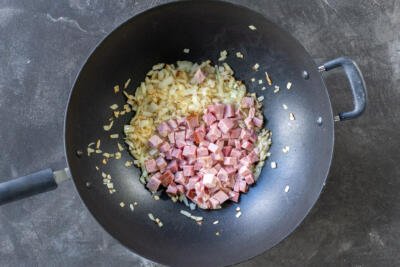 Onions and ham in a wok.