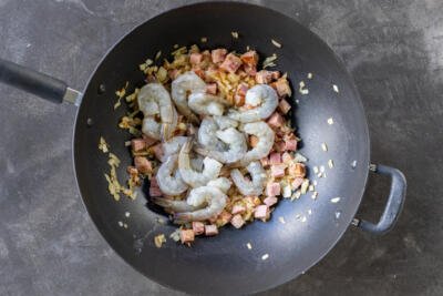 Shrimp added to the wok with ham and onions.