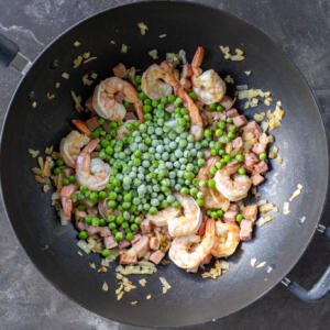 Peas added to the cooking ingredients in a wok.
