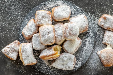 Beignets with powder sugar on a serving tray.