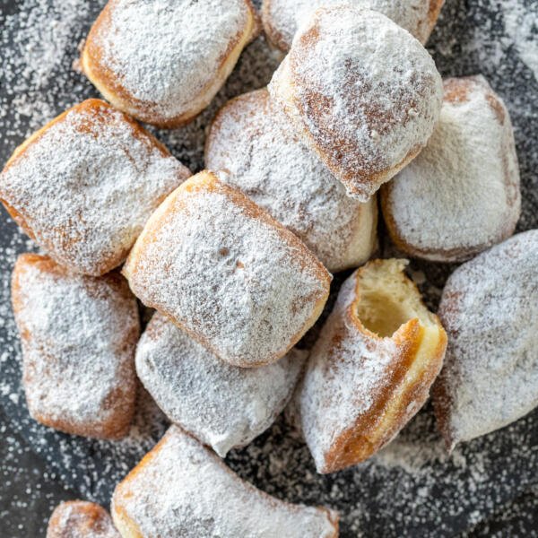 Beignets with powdered sugar on a tray.