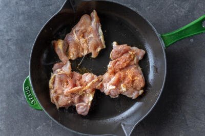 Raw chicken frying on a pan.
