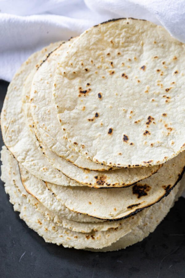 Corn tortillas on a tray with towel.