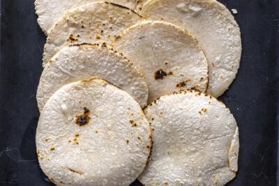 Cooked tortillas on a baking sheet.