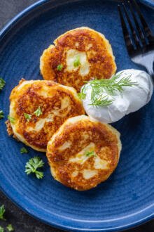 Mashed Potato Pancakes on a plate with herbs dipping sauce.