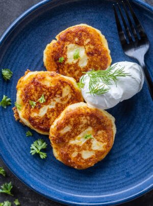 Mashed Potato Pancakes on a plate with herbs dipping sauce.