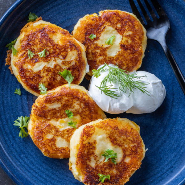 Mashed Potato Pancakes on a plate with sauce and fork.