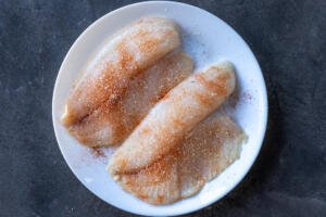 Seasoned tilapia on a plate.