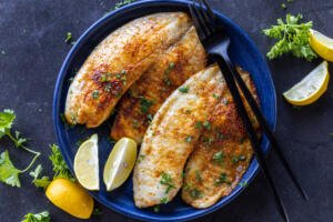 Air Fryer Tilapia on a plate with herbs.