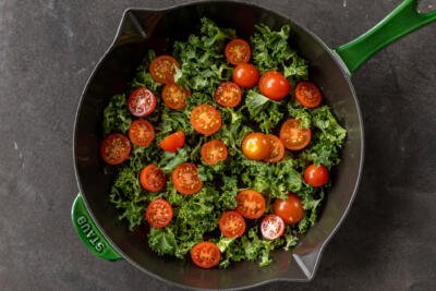 Kale and cherry tomatoes in a pan.