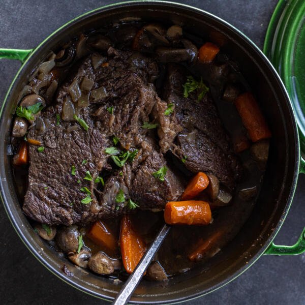 Dutch Oven Pot Roast with a spoon and herbs.
