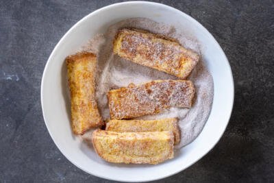 Toasts in a bowl with sugar.
