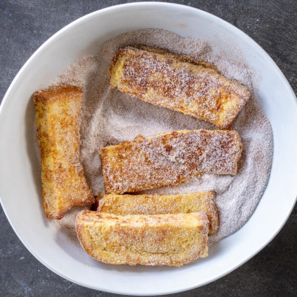 Toasts in a bowl with sugar.