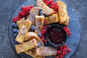 French Toast Sticks with berries on a serving tray.