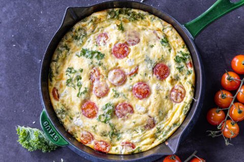 Baked Frittata in a pan with tomatoes next to it.