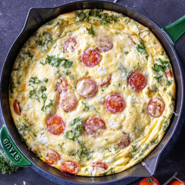 Baked Frittata in a pan with tomatoes next to it.