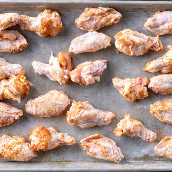 Seasoned wings on a baking pan.