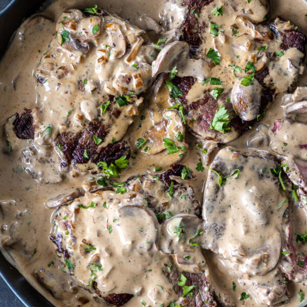 Steak Diane in a pan with herbs.