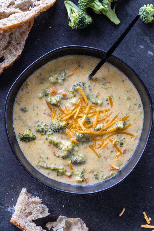 Broccoli Cheddar Soup with cheddar cheese and a spoon. 