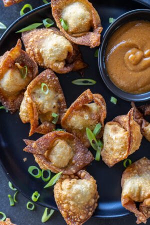 Fried Wontons on a serving tray with sauce.