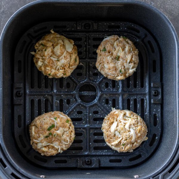 Shaped crab cakes in an air fryer basket.