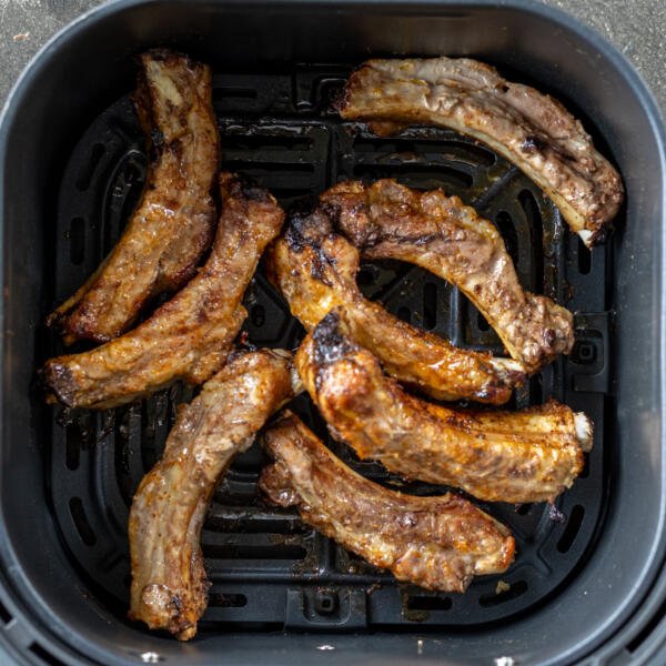 Cooked pork ribs in an air fryer basket.