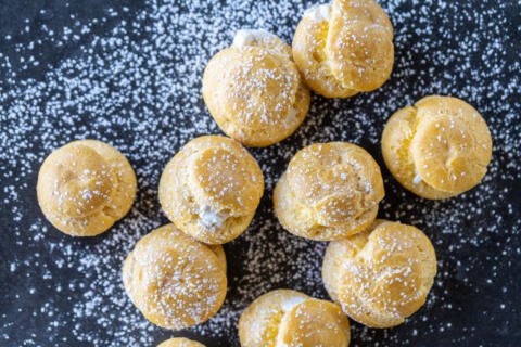 Several of Cream Puffs with powdered sugar sprinkles.
