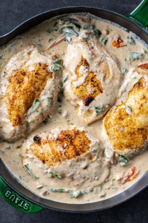 Chicken in a creamy tomato spinach sauce in a pan.