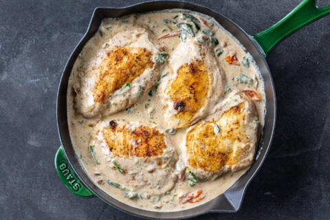 Cooked chicken with creamy spinach sauce in a pan.
