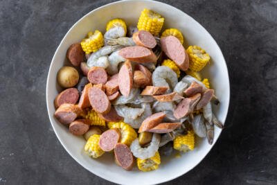 Shrimp and sausage with potatoes, corn in a large bowl.