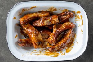 Pork ribs in a bowl with bbq sauce.
