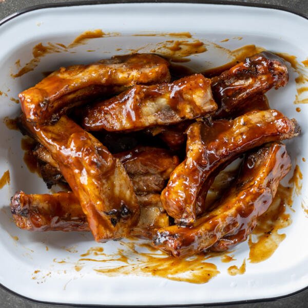 Pork ribs in a bowl with bbq sauce.