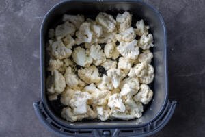 Air fryer basket with seasoned Cauliflower.