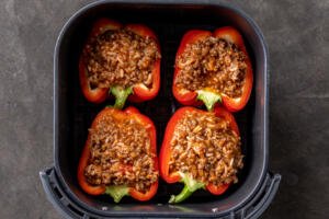Stuffed peppers in an air fryer basket.