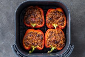 Cooked Stuffed peppers in an air fryer basket.