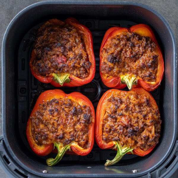Cooked Stuffed peppers in an air fryer basket.